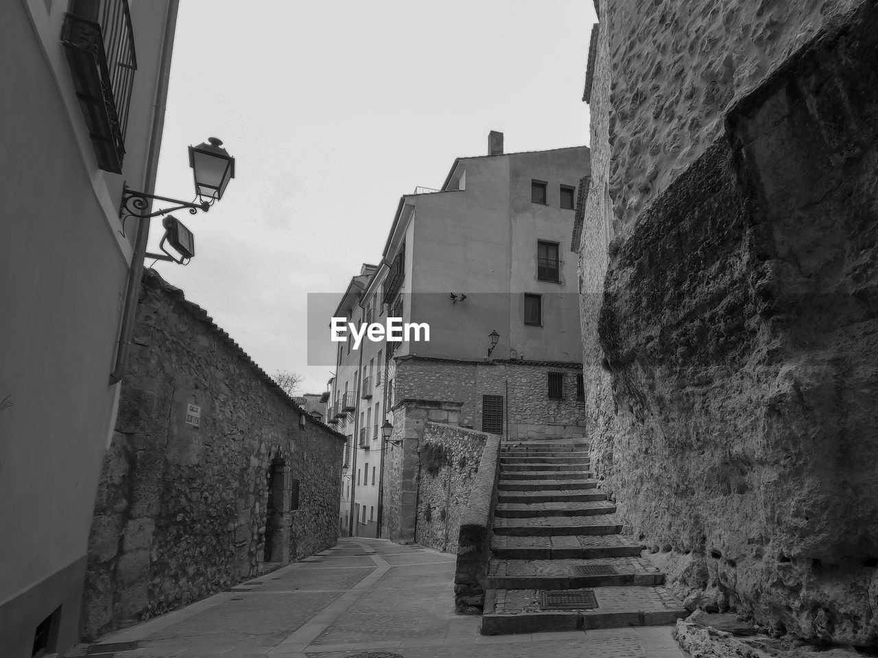 Black and white photo of stairs and an empty street in the old town of cuenca, spain on a cloudy day