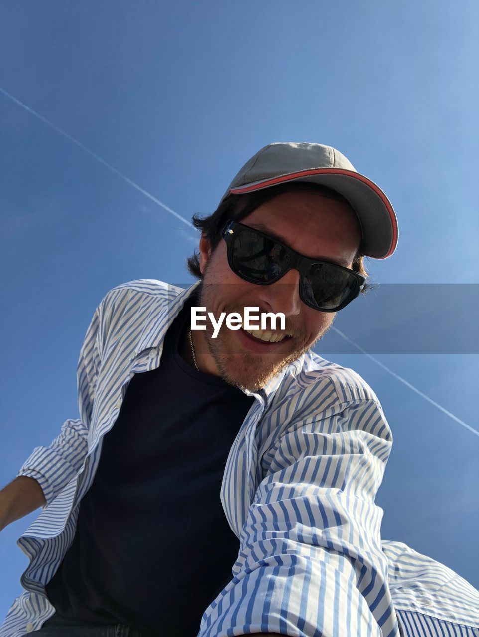 Low angle portrait of man wearing sunglasses against sky