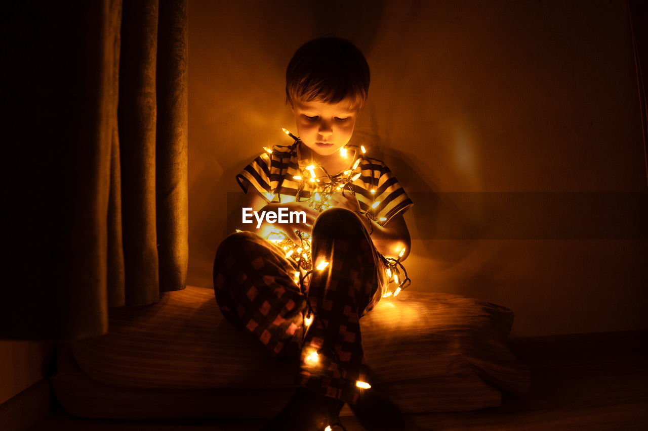 Full length of boy with illuminated lights at home