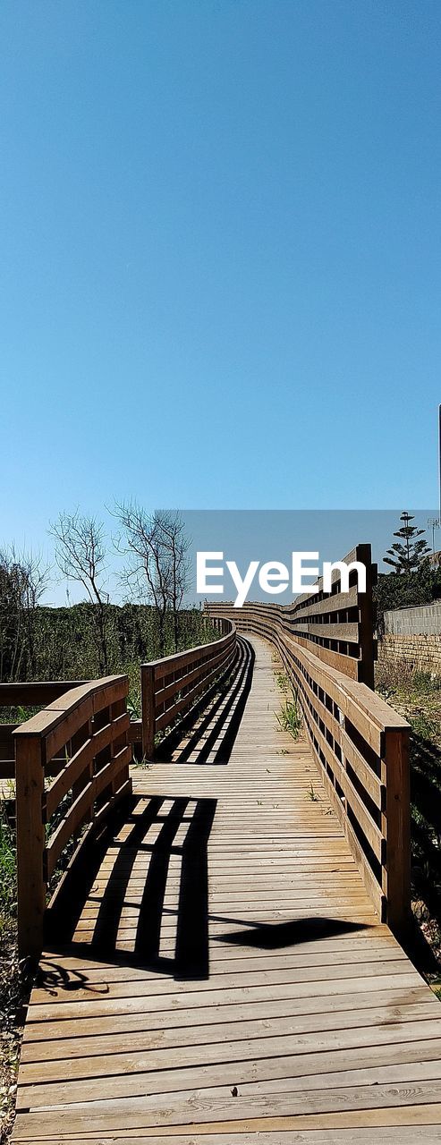 EMPTY WOODEN FOOTBRIDGE AGAINST CLEAR SKY