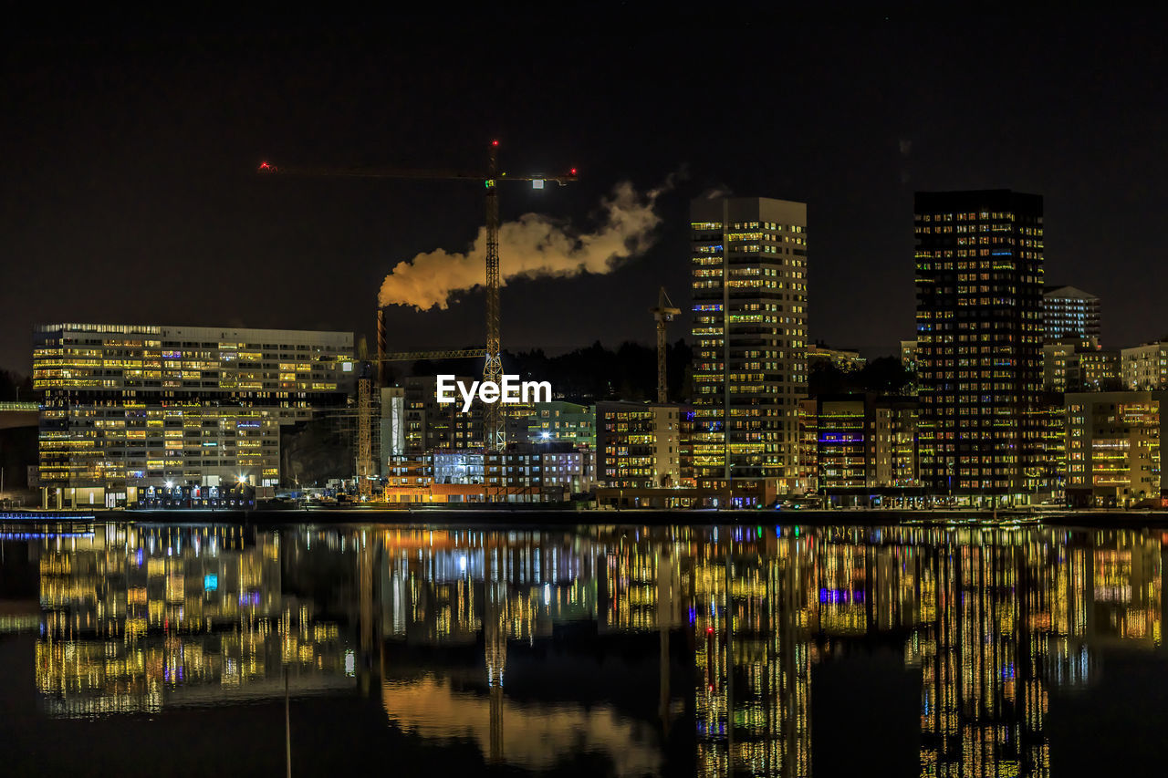 REFLECTION OF ILLUMINATED BUILDINGS IN RIVER AT NIGHT