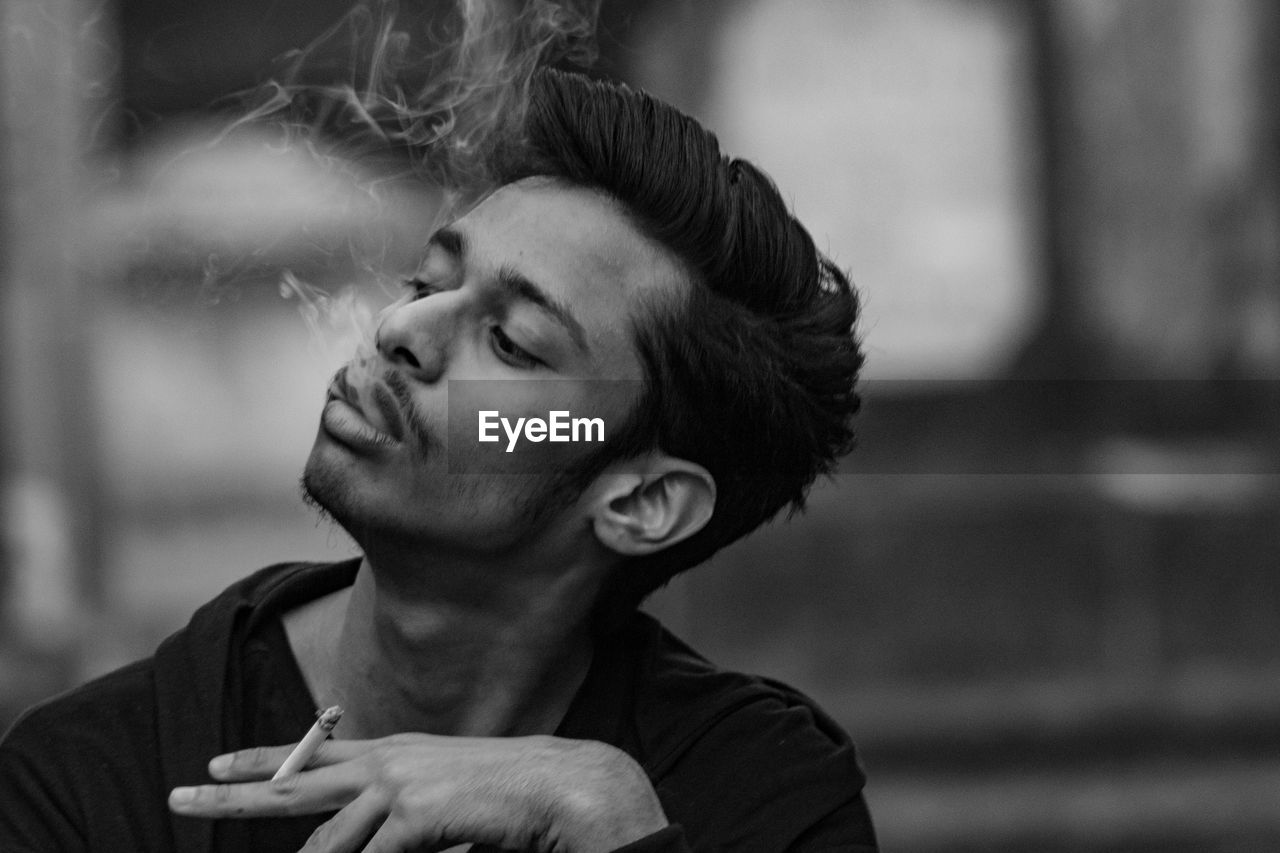 Portrait of young man smoking outdoors