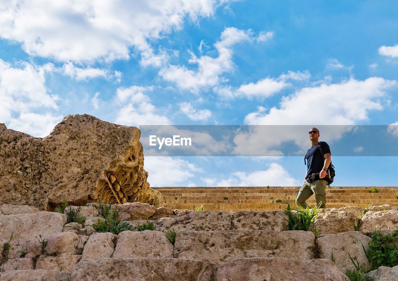Low angle view of man standing on old ruins against sky