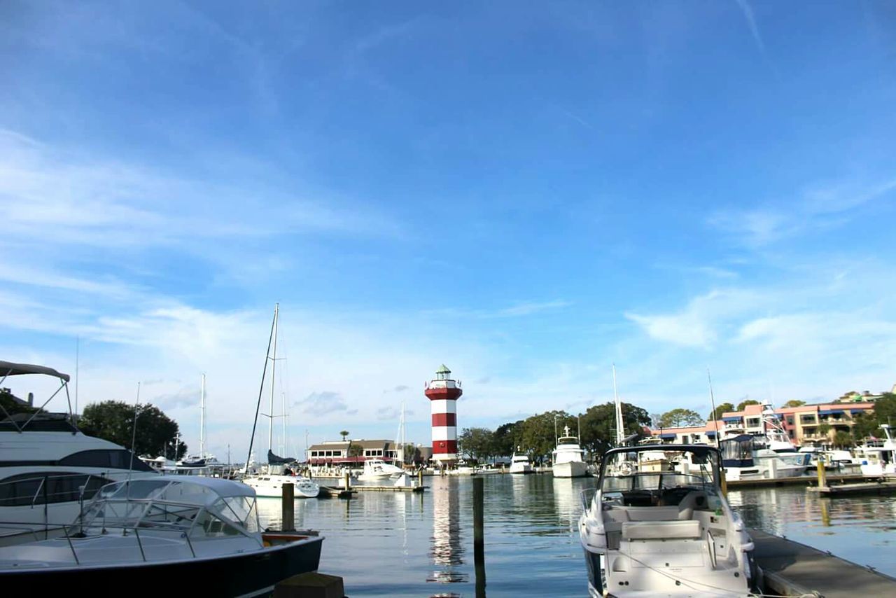 Boats moored at harbor against sky