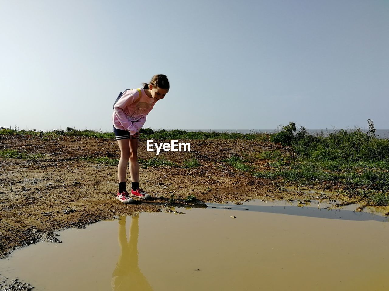 FULL LENGTH OF GIRL STANDING ON SHORE AGAINST SKY