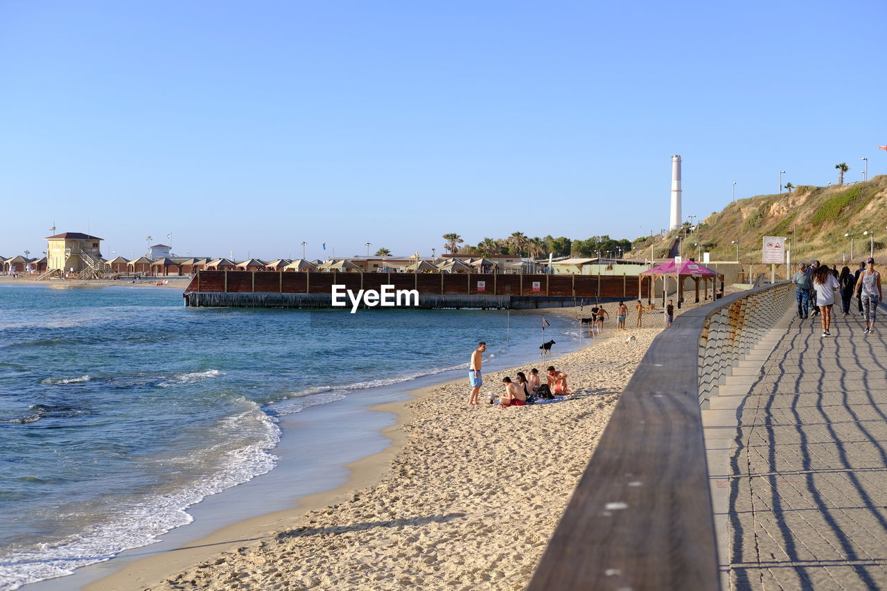 People at beach against clear sky