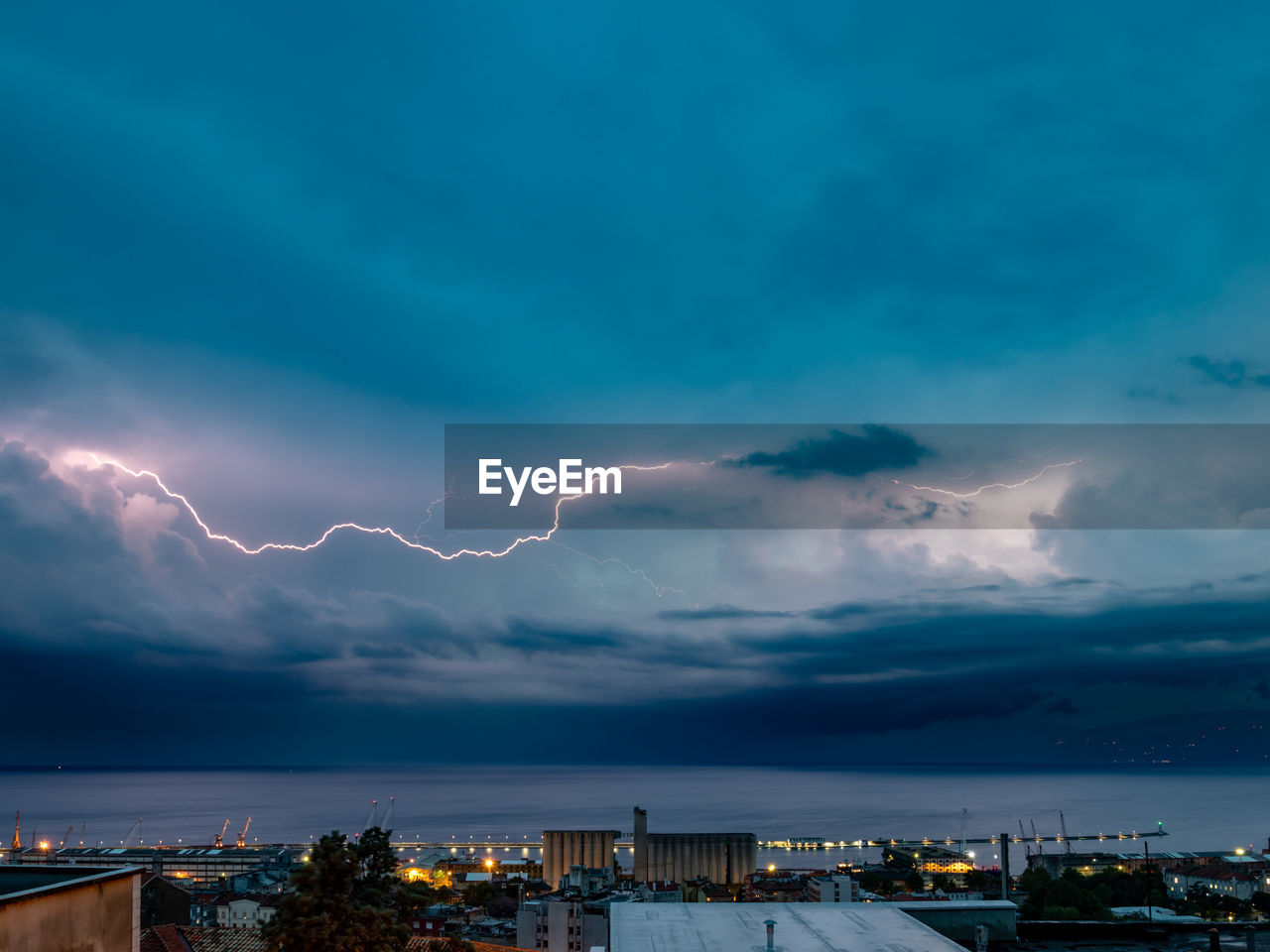 Lightning over illuminated buildings in city at night