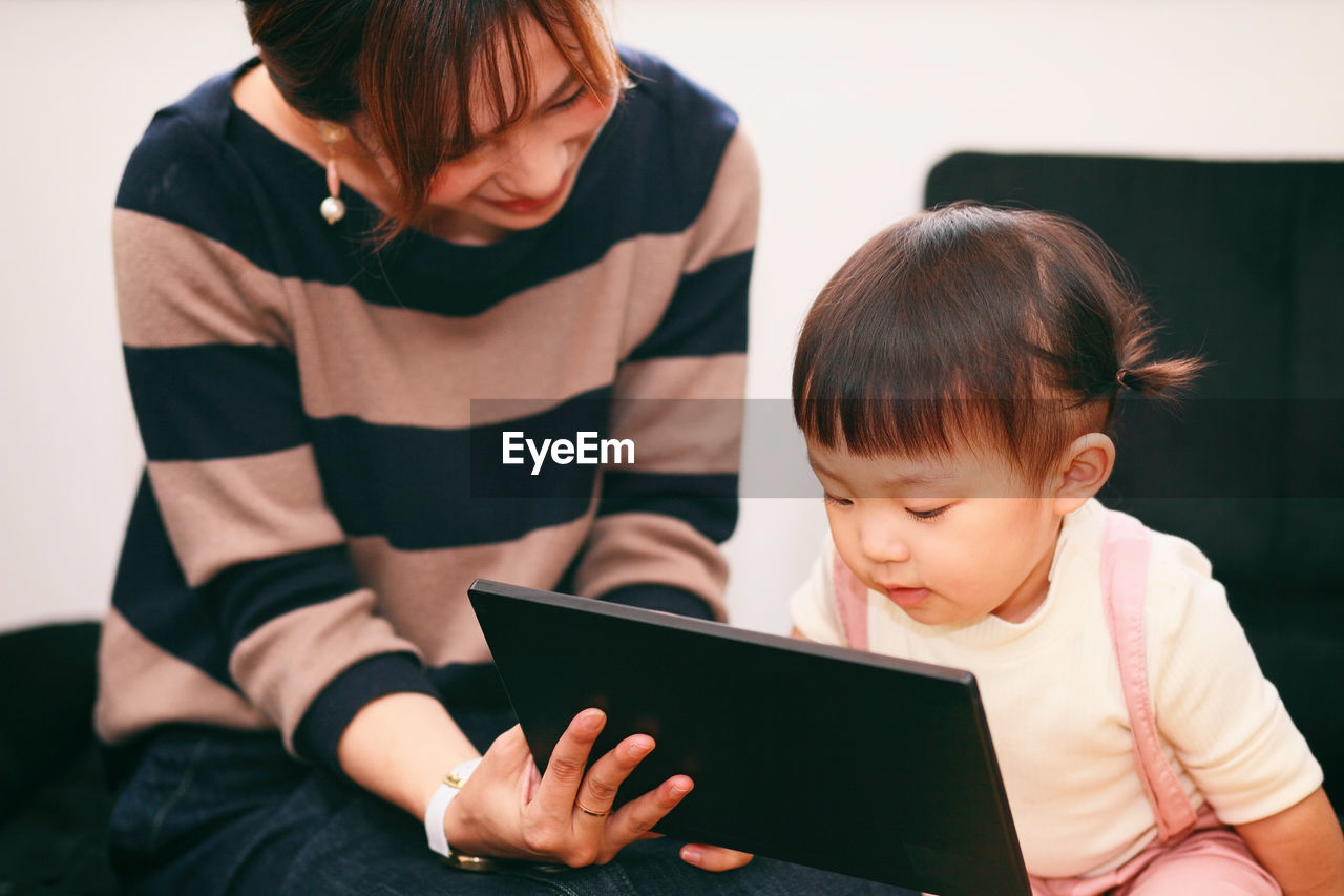 Mother with daughter using digital tablet at home