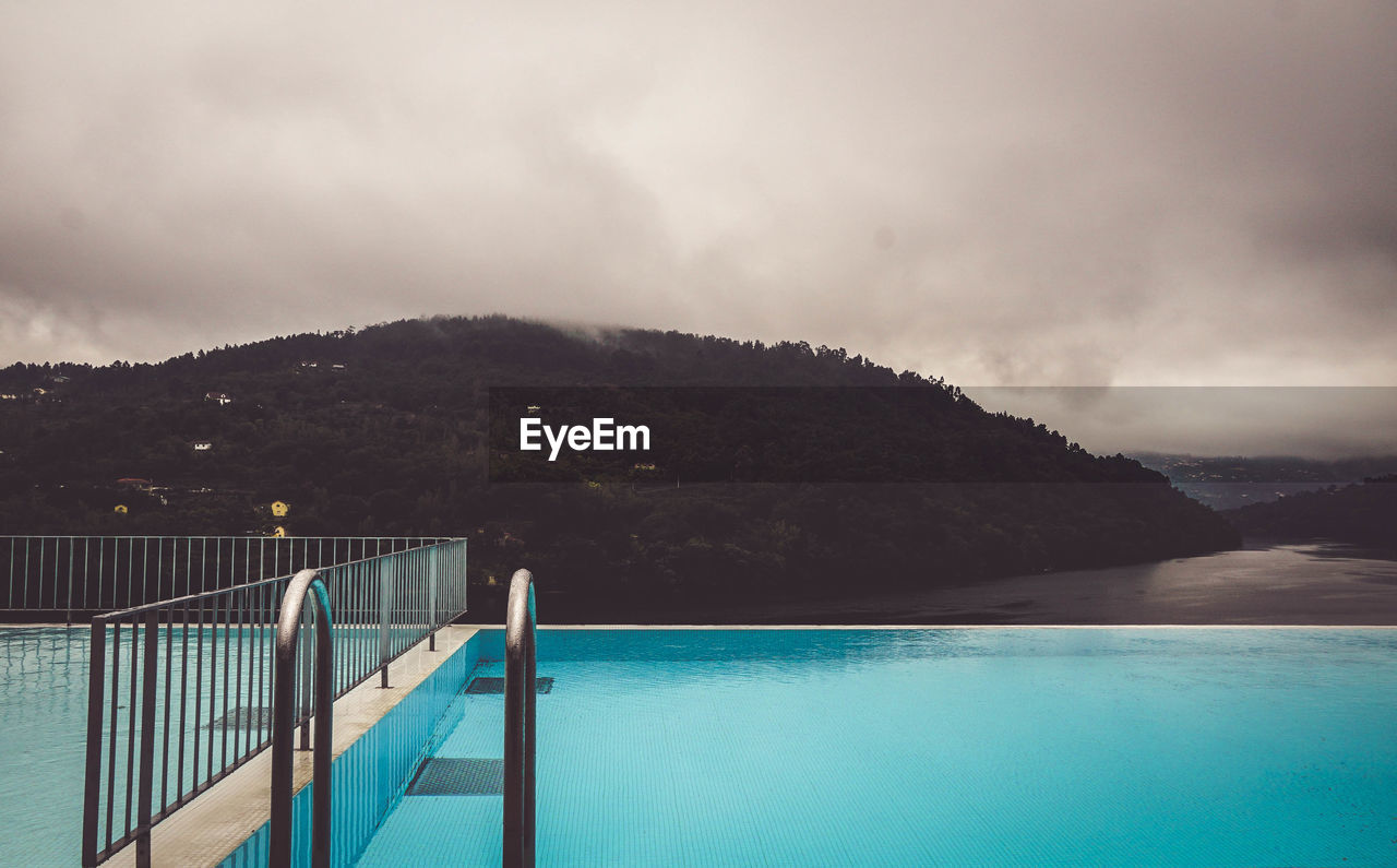 Swimming pool by sea against sky