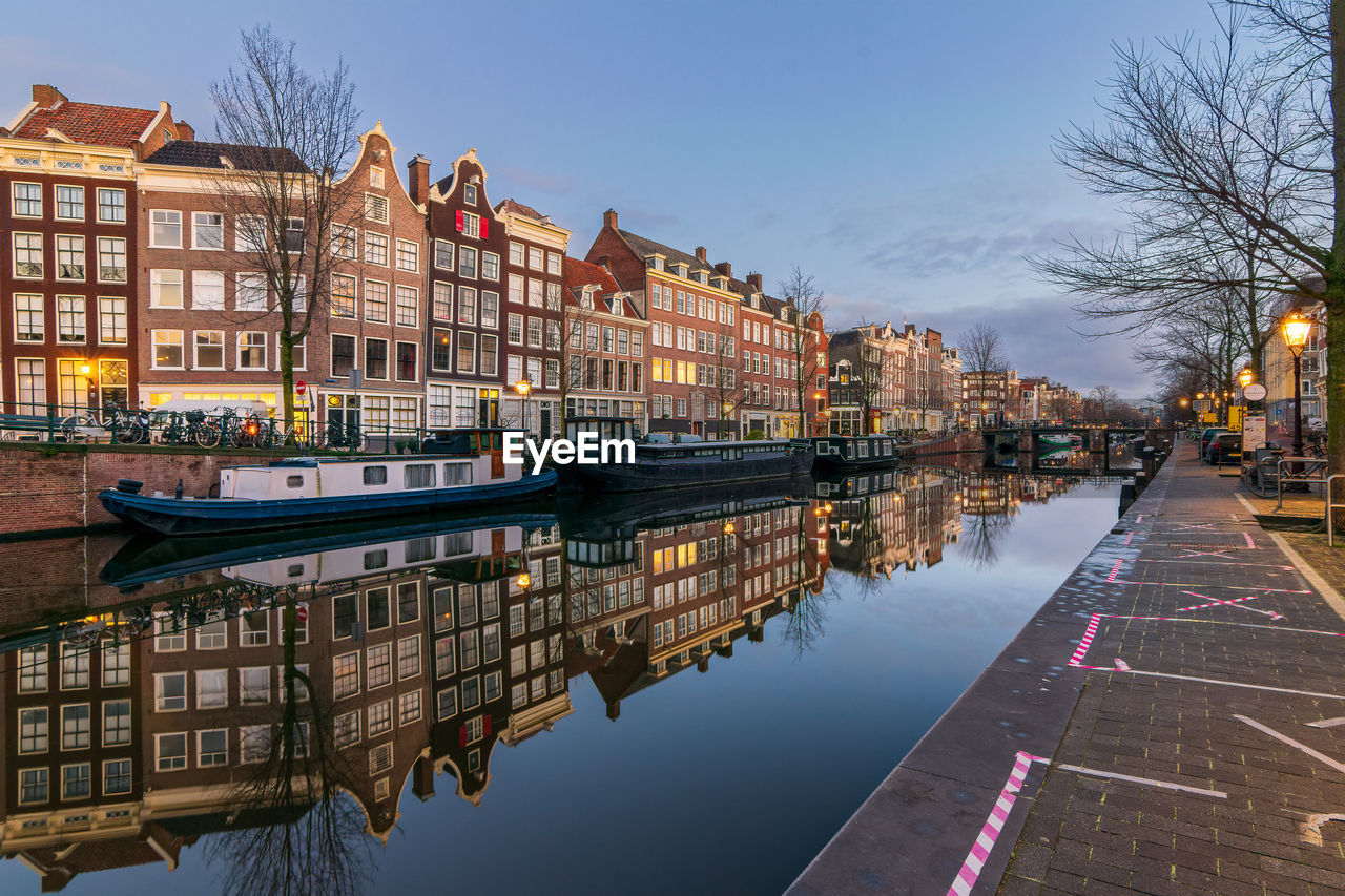 Canal by buildings against sky in city