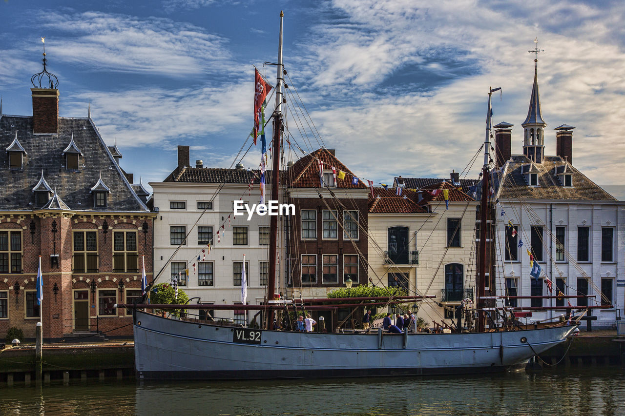 BUILDINGS WITH WATERFRONT AGAINST CLOUDY SKY