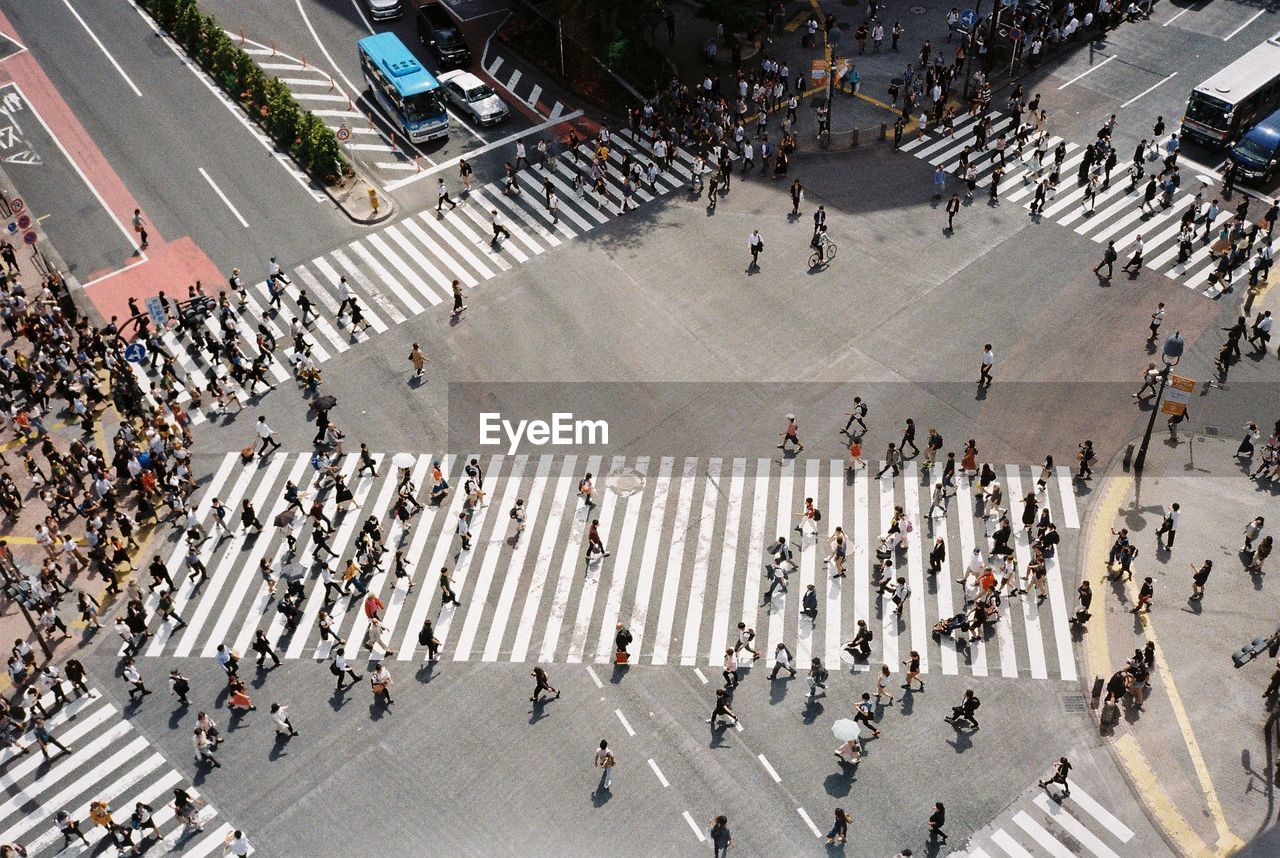 HIGH ANGLE VIEW OF CROWD CROSSING ROAD