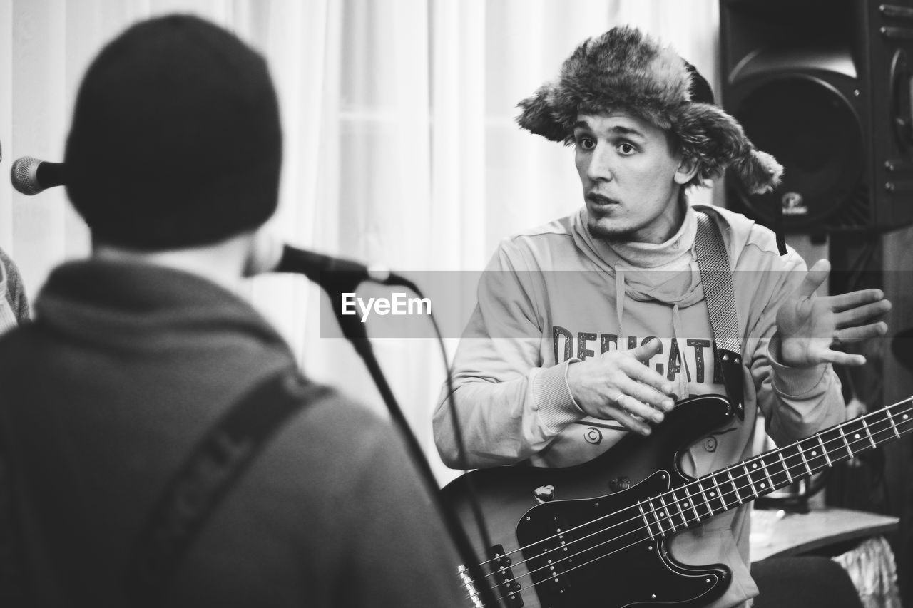 PORTRAIT OF MAN PLAYING GUITAR AT HOME