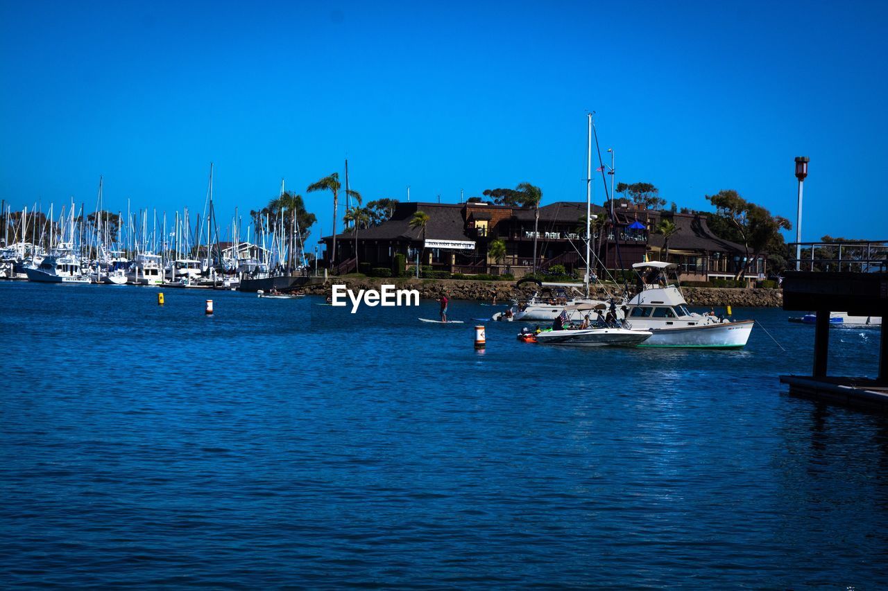 SAILBOATS MOORED IN SEA AGAINST CLEAR BLUE SKY