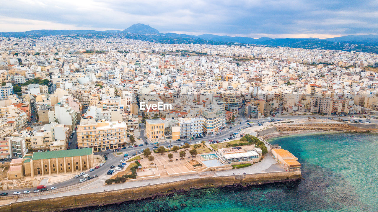 HIGH ANGLE VIEW OF CITY AGAINST SEA