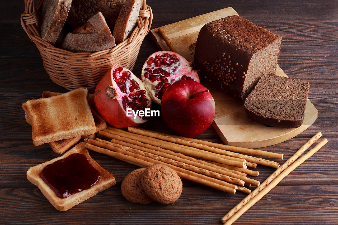 Different buns of fresh bread and spikelets of wheat on a brown vintage background