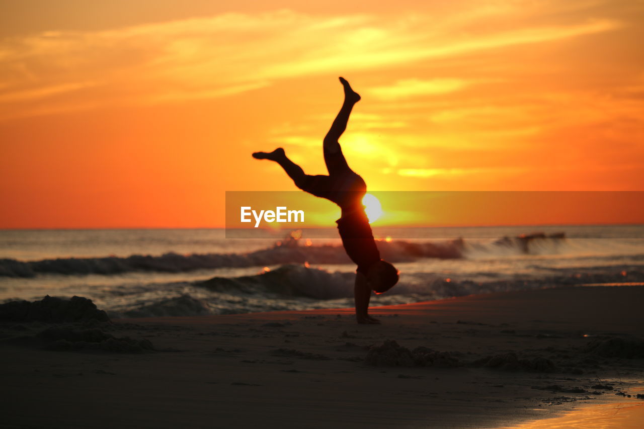 Full length of silhouette man on beach against sky during sunset