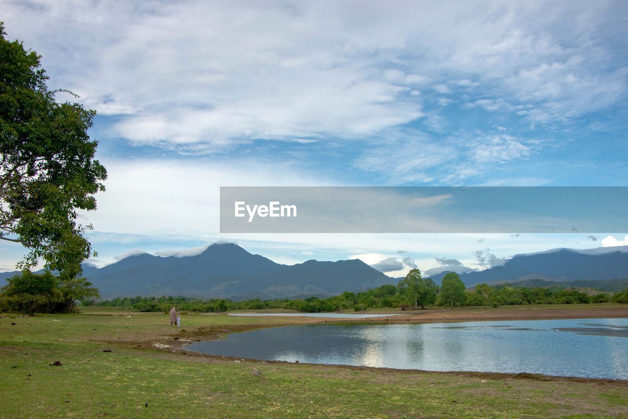 water, sky, mountain, environment, cloud, scenics - nature, landscape, beauty in nature, lake, nature, plant, reservoir, land, tree, body of water, mountain range, travel destinations, tranquility, travel, grass, reflection, tranquil scene, no people, tourism, shore, blue, outdoors, beach, non-urban scene, day, summer, trip, vacation, holiday, rural area, forest, idyllic, highland