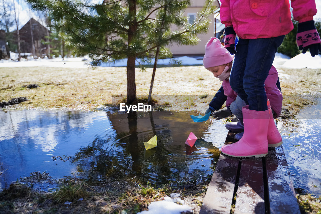 REAR VIEW OF WOMAN STANDING BY WATER