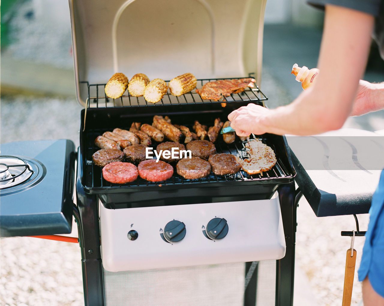 PERSON HOLDING FOOD ON BARBECUE GRILL AT KITCHEN