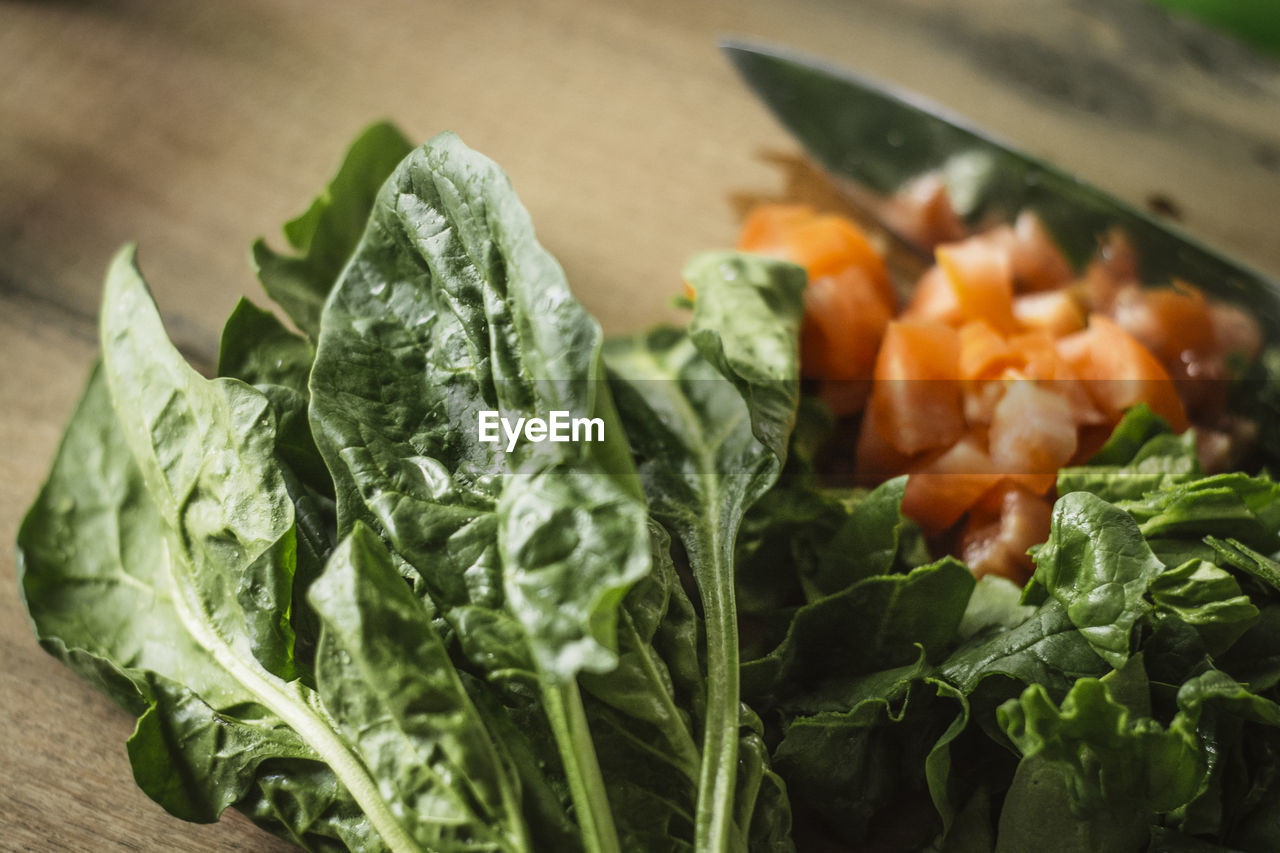 Close-up of chopped spinach and tomatoes on table