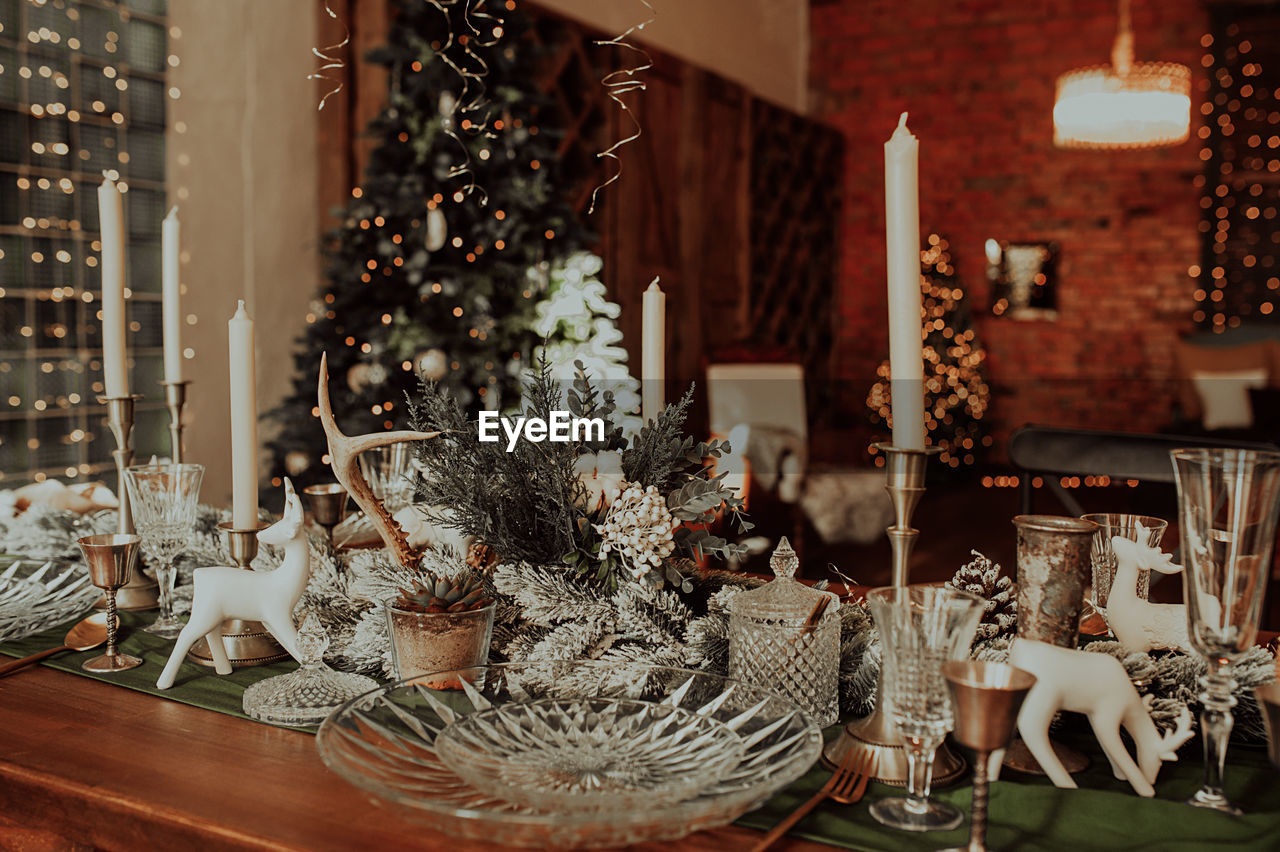 Chic christmas table setting in beige and wooden colors, glassware, candles. christmas interior