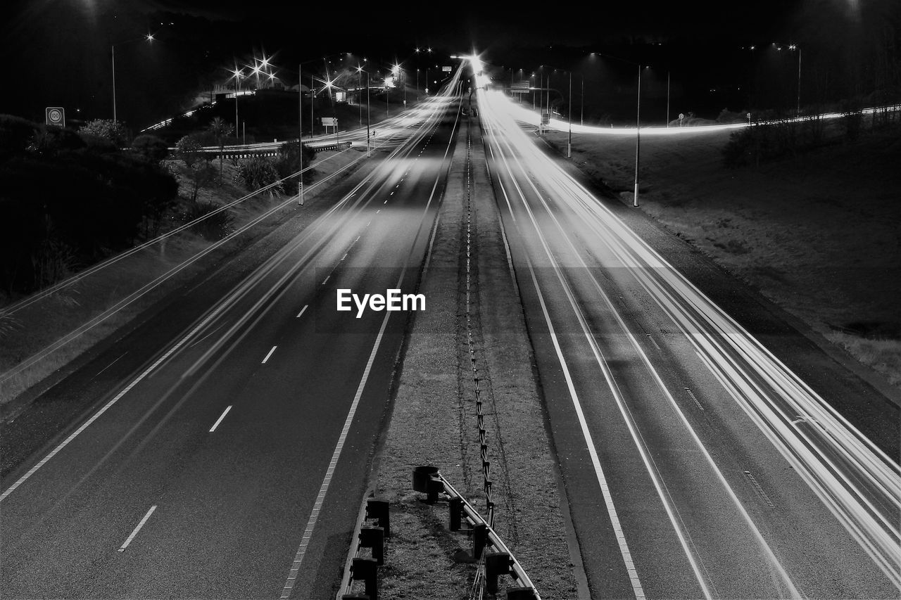 HIGH ANGLE VIEW OF LIGHT TRAILS ON ROAD IN CITY AT NIGHT