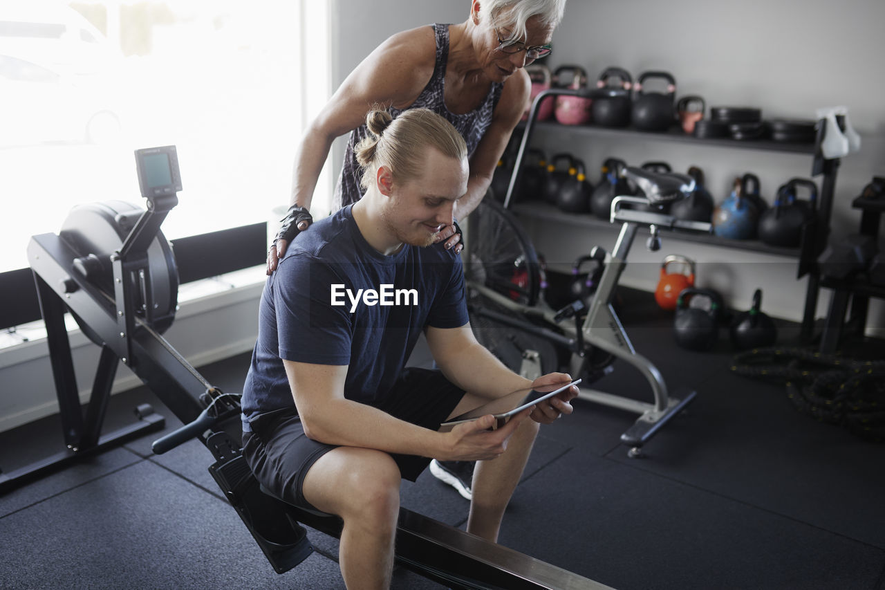 Man and woman looking at digital tablet in gym