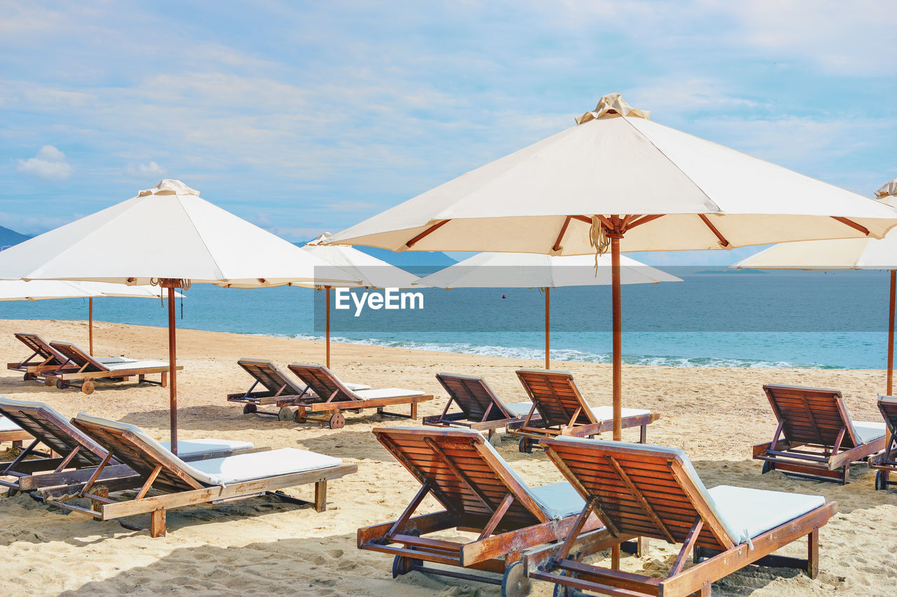 DECK CHAIRS ON BEACH AGAINST SEA