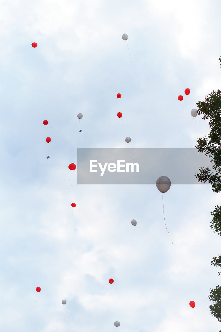 Low angle view of helium balloons against sky