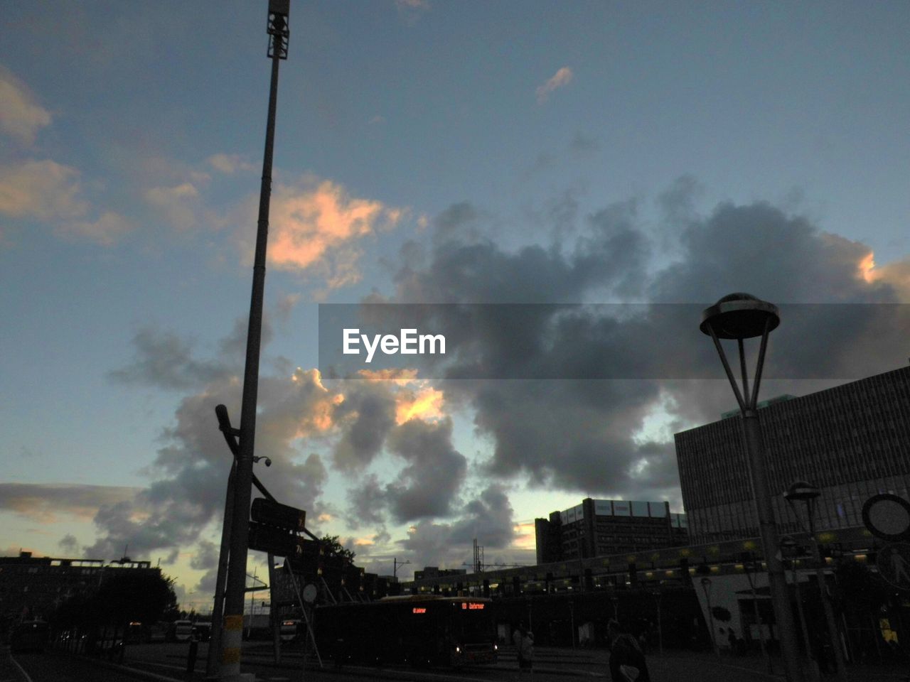 LOW ANGLE VIEW OF ILLUMINATED STREET LIGHTS AGAINST CLOUDY SKY