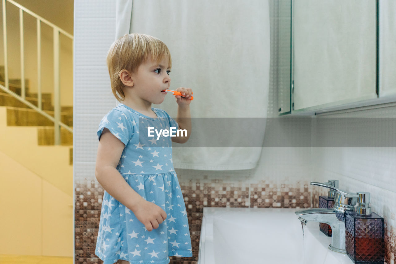 Little toddler girl brushes her teeth in the bathroom.