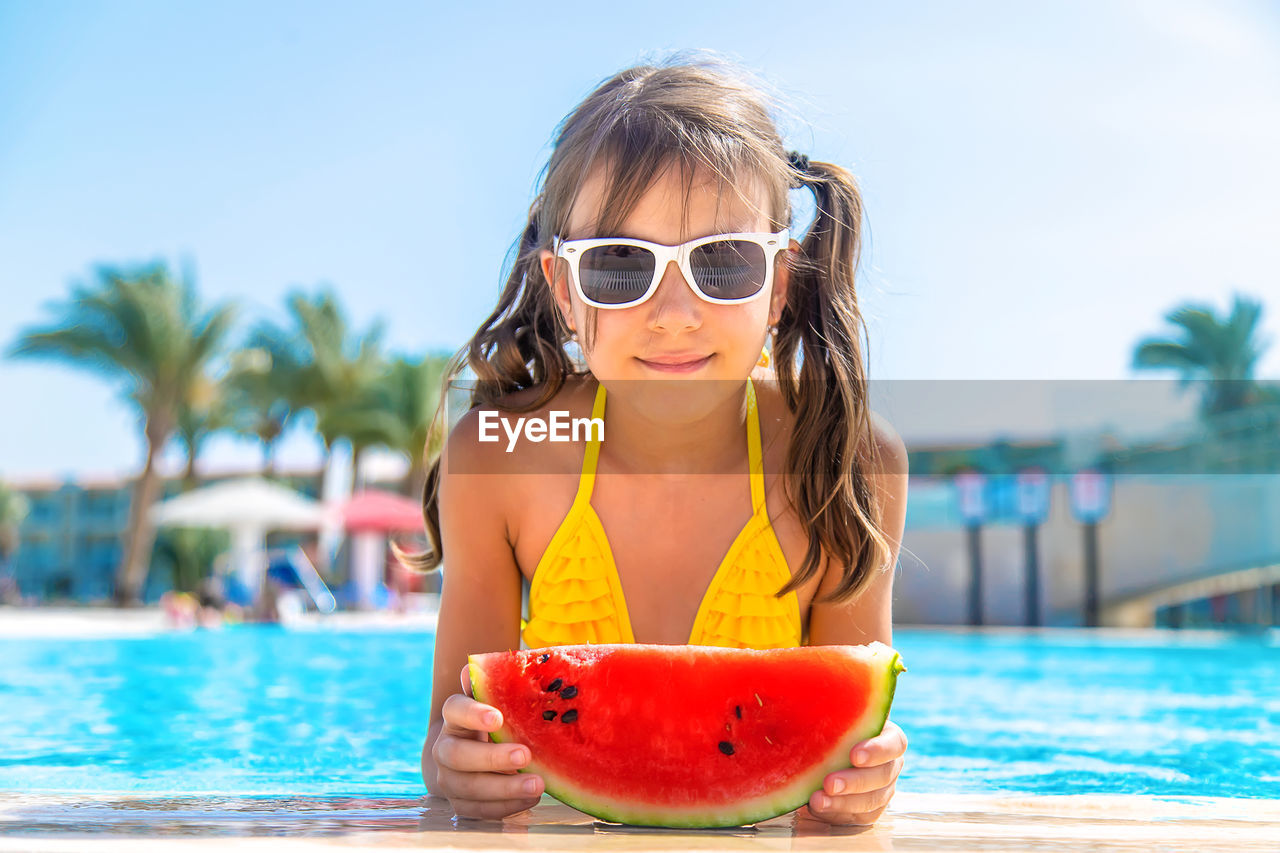 Smiling girl with watermelon by swimming pool