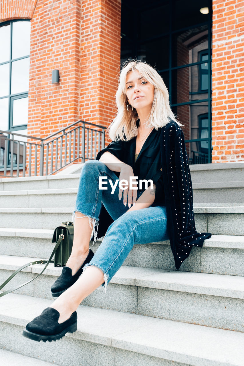 Full length of young woman sitting on staircase