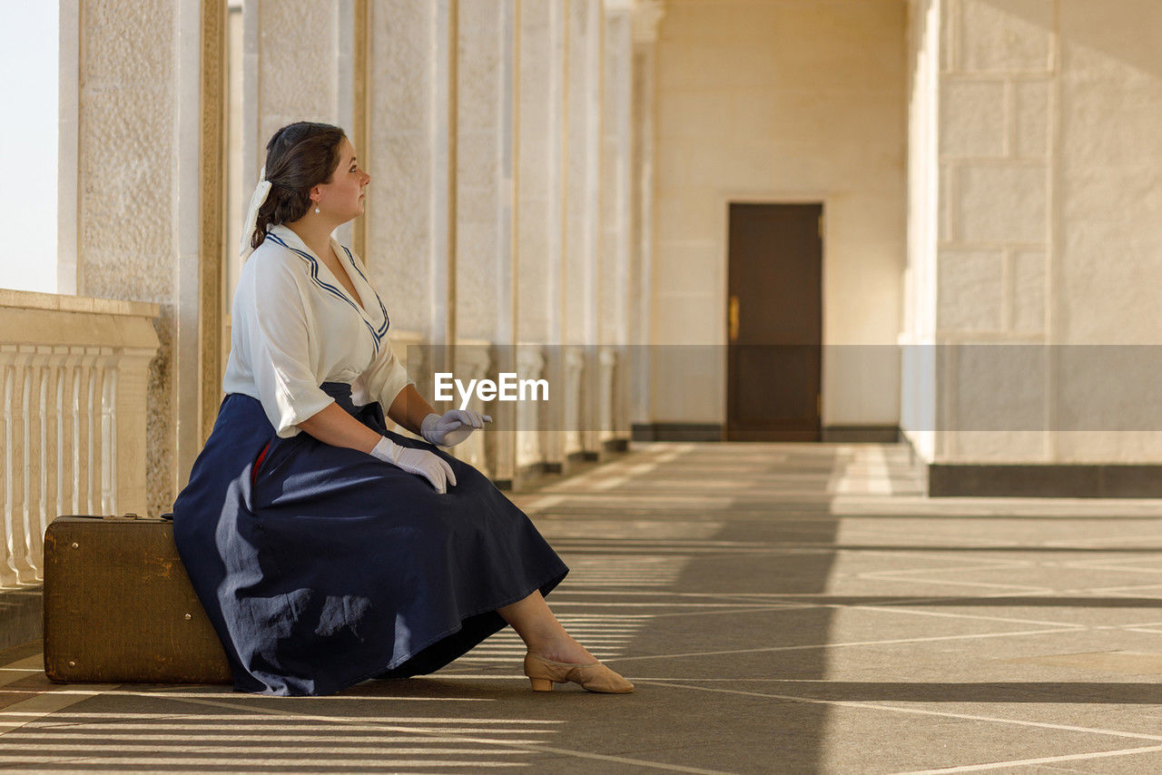 side view of young woman sitting on steps
