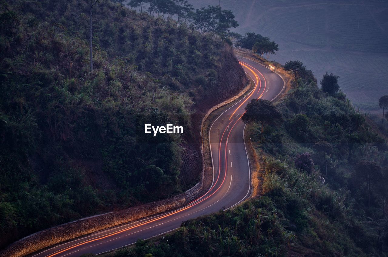 High angle view of light trails on mountain road during sunset