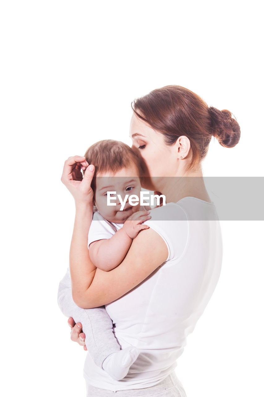 PORTRAIT OF MOTHER AND BABY AGAINST WHITE BACKGROUND