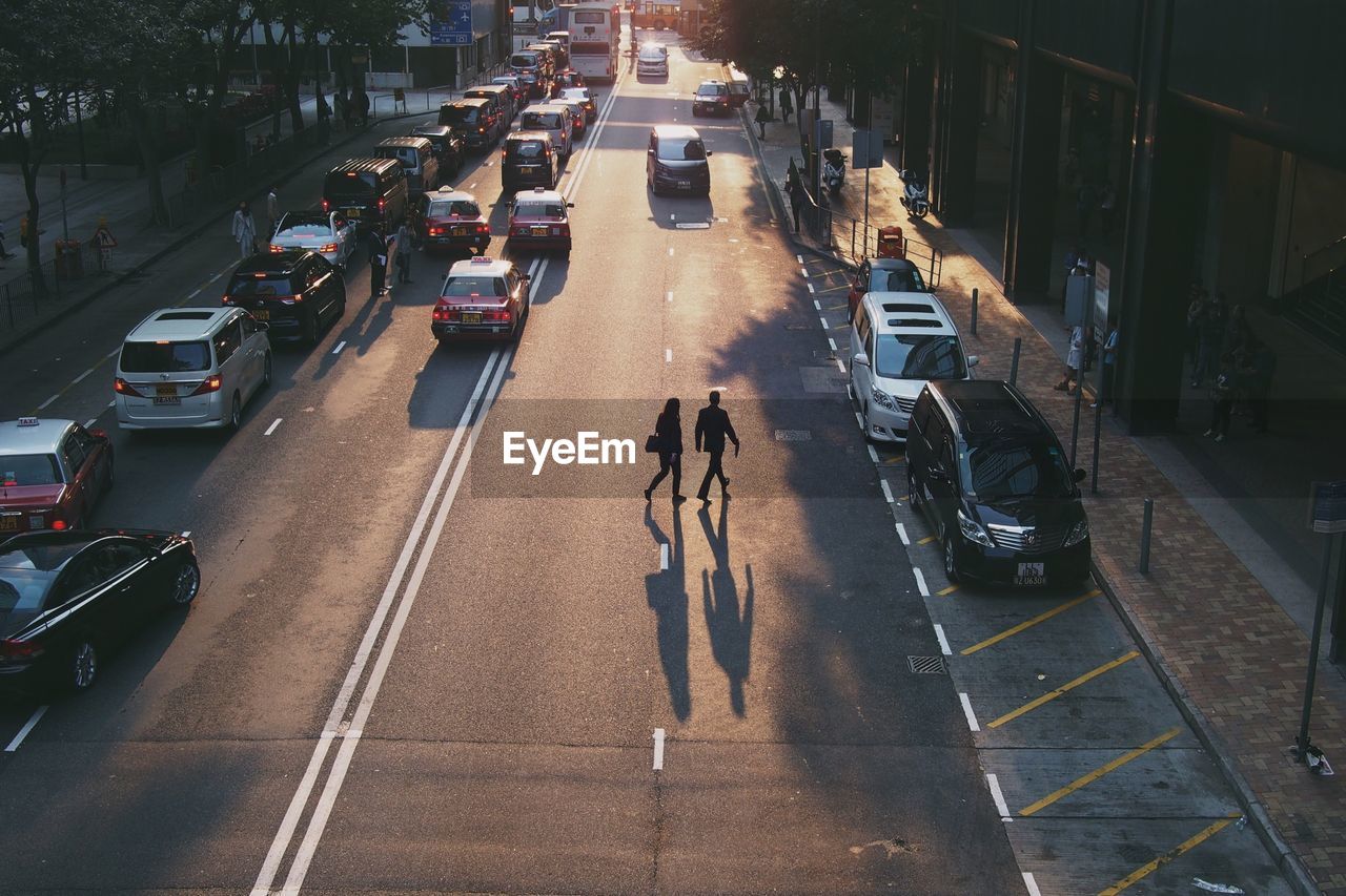 Aerial view of young couple crossing crowded street at sunset