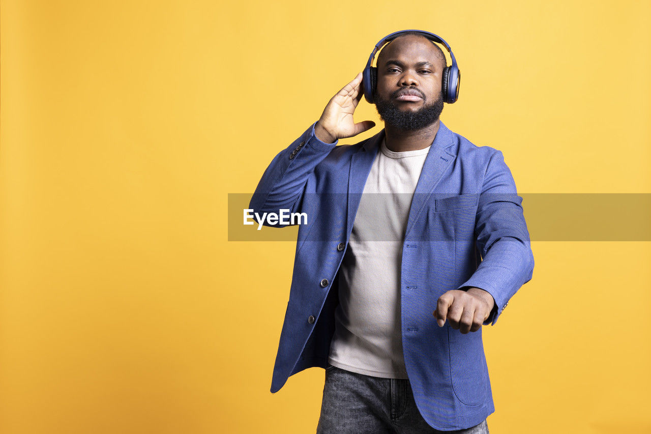 portrait of young man standing against yellow background