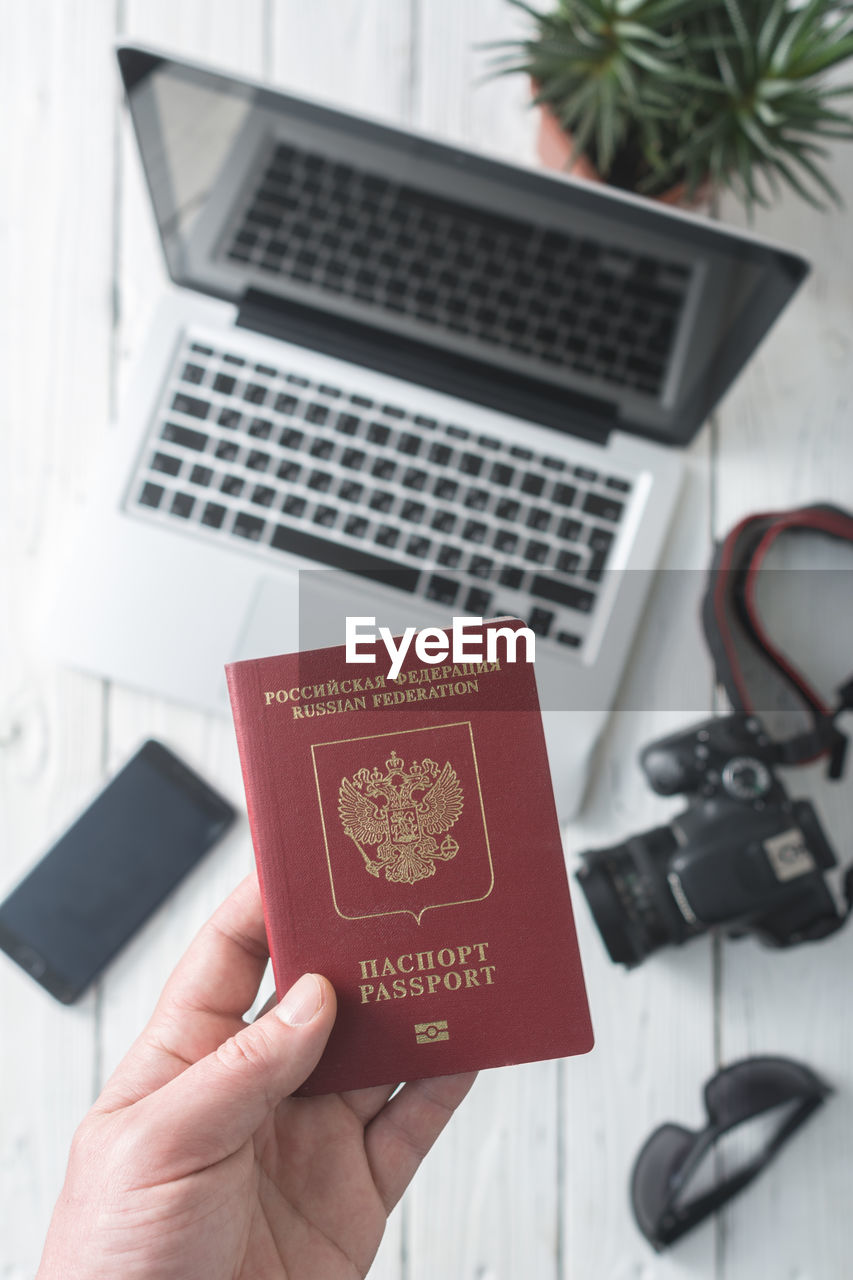 Directly above shot of cropped hand holding passport over table