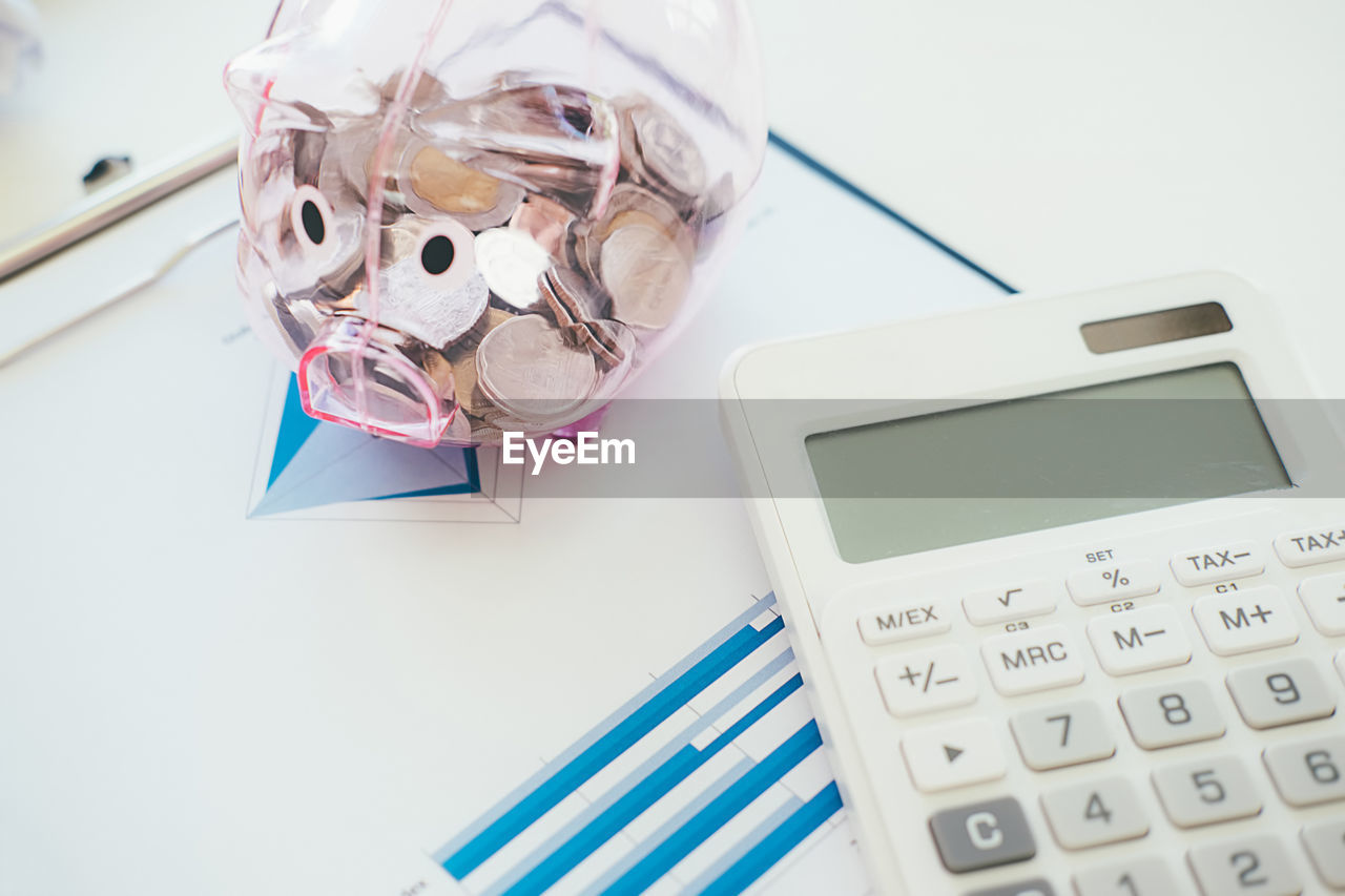 High angle view of calculator with piggy bank on table