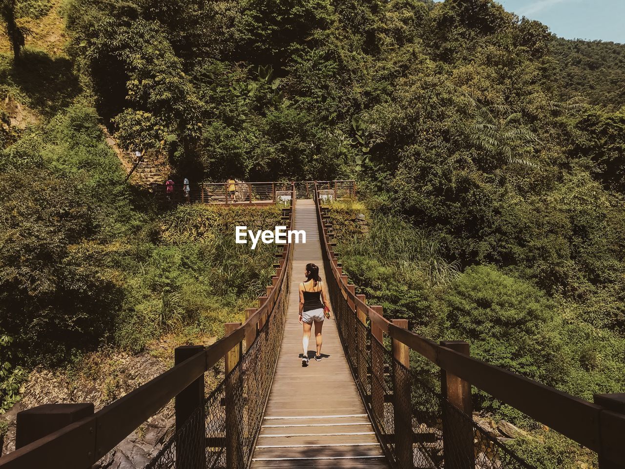 Rear view of woman walking on footbridge