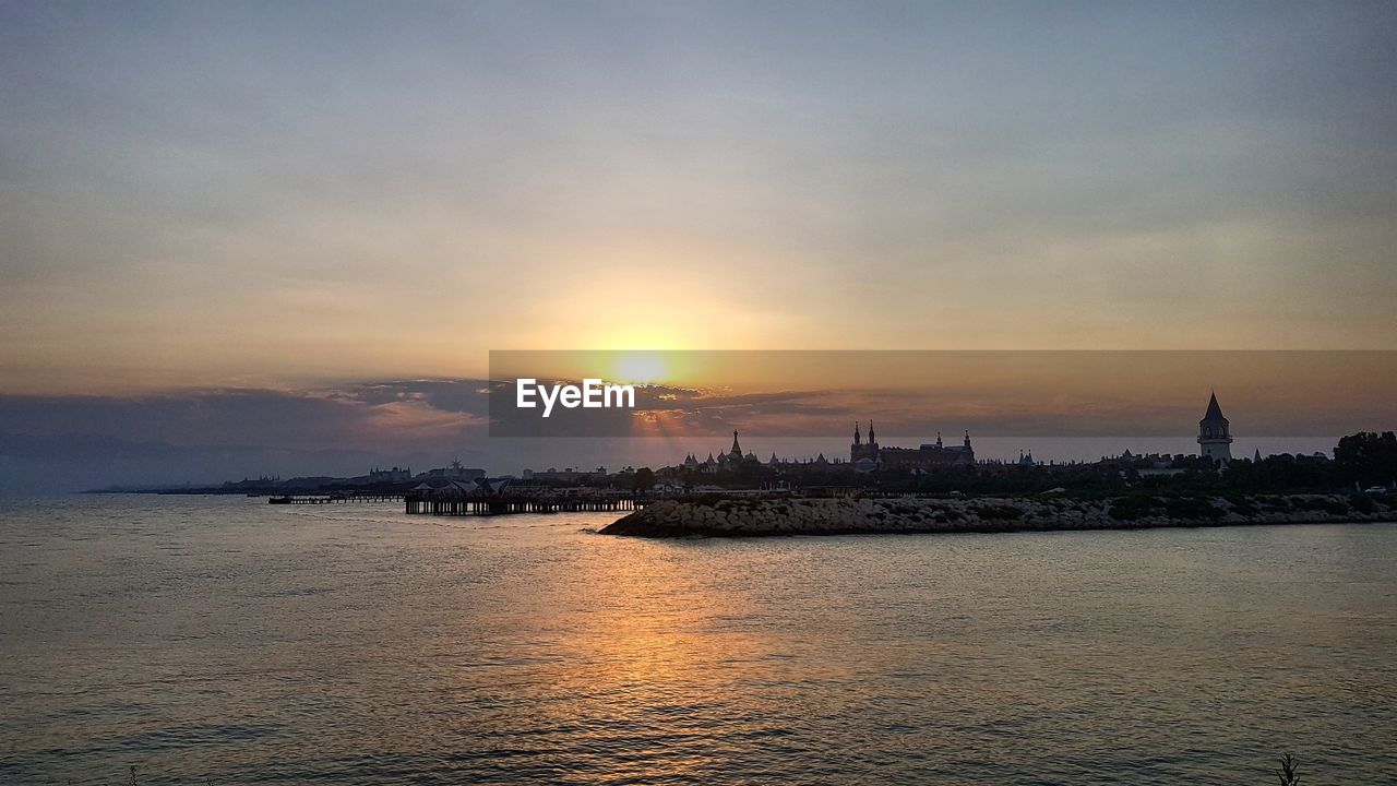 SCENIC VIEW OF SEA DURING SUNSET IN CITY