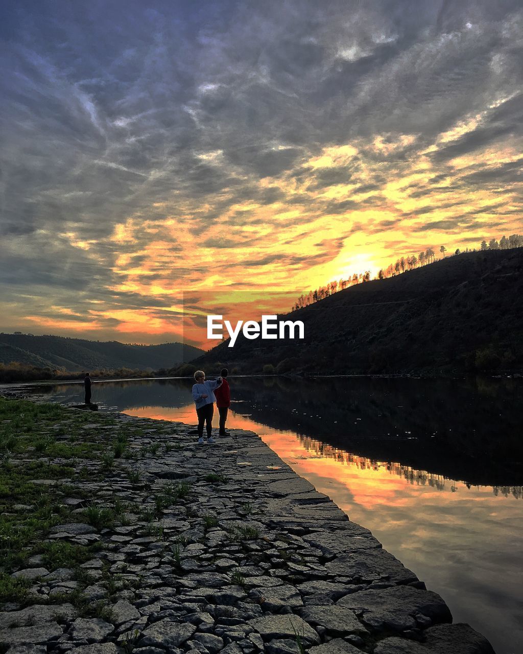 Mature couple standing by lake during sunset