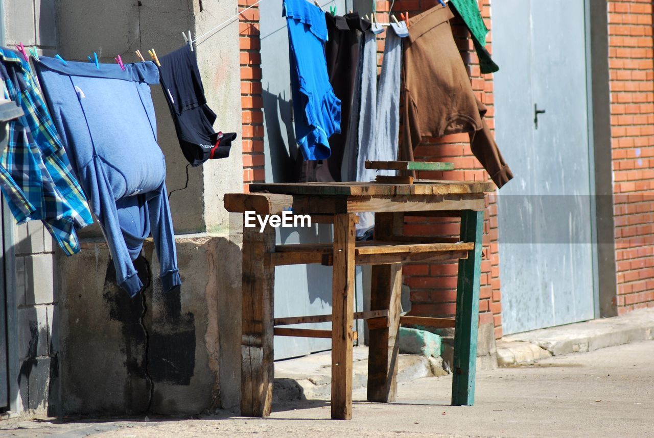 Clothes drying on string by wooden table outside house