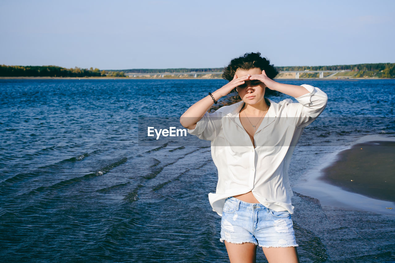 YOUNG WOMAN STANDING IN SEA