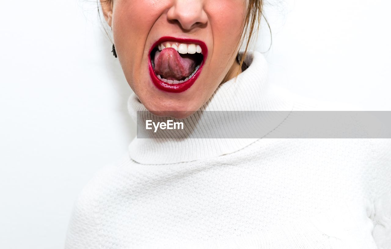 Cropped image of woman sticking out tongue against white background