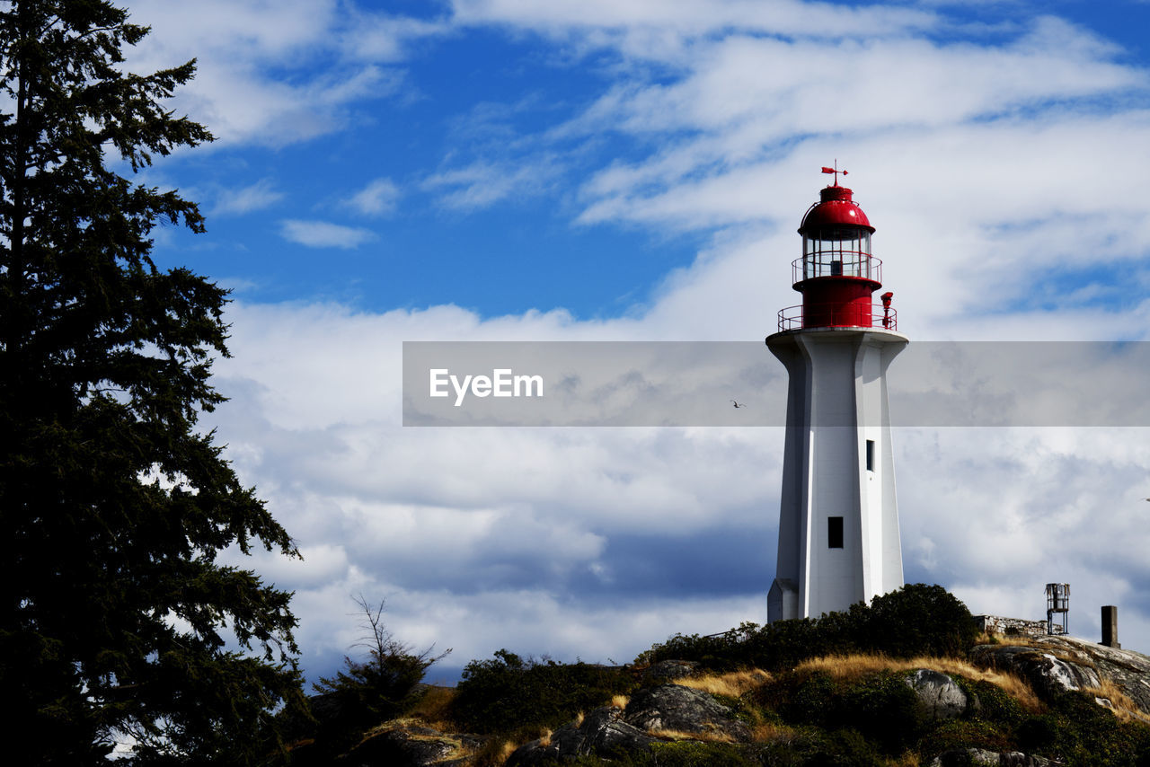 lighthouse, guidance, tower, architecture, building exterior, built structure, security, protection, sky, building, cloud, nature, observation tower, plant, tree, no people, travel destinations, beach, sea, water, land, outdoors, day, travel, coast, house, red, communication, scenics - nature, surveillance, assistance, blue, non-urban scene, environment, low angle view, coastline