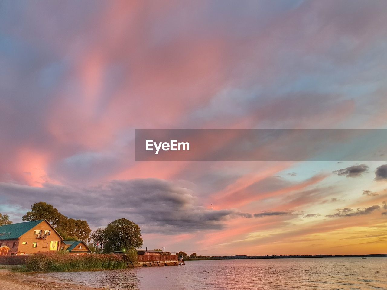 SCENIC VIEW OF SEA BY BUILDING AGAINST ORANGE SKY