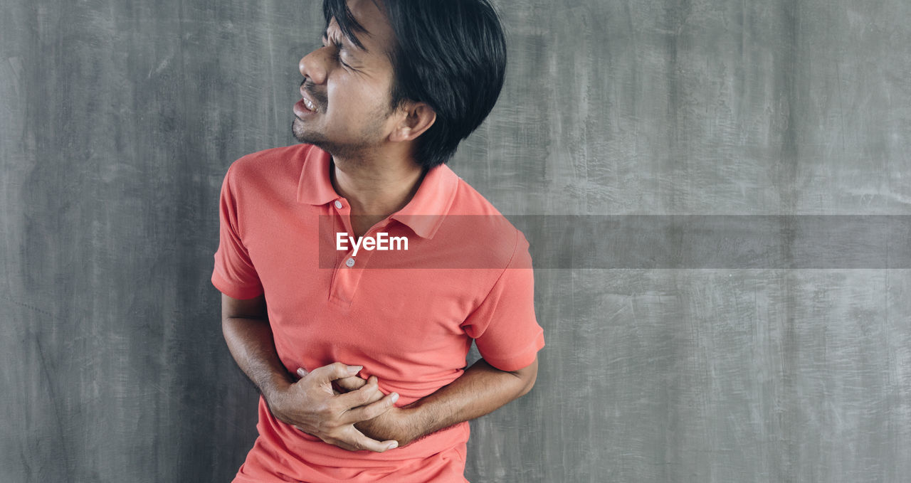 MID ADULT MAN STANDING AGAINST WALL IN A ROOM